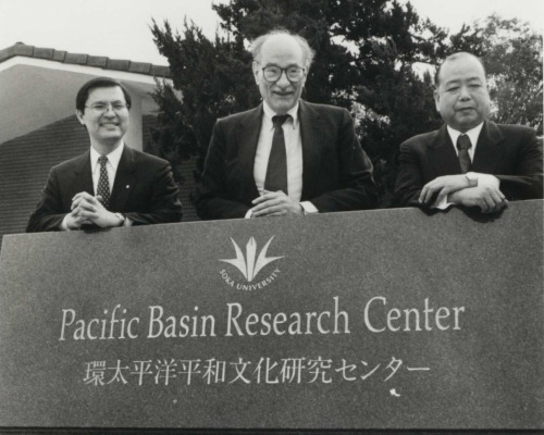 Three men stand behind the PBRC sign to commemorate its opening.