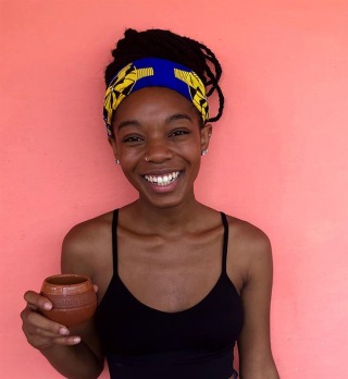 Student holding cup smiling at camera