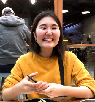 Student wearing yellow sweater smiling at camera