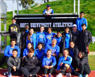 Group photo of Soka's Cross Country Team in front of a sign that reads "Soka University Athletics"