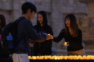Students hand out and receive candles during the vigil for Lucas Colombo