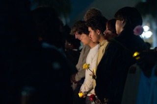 Students look to be in deep reflection, holding yellow roses during Lucas' vigil.