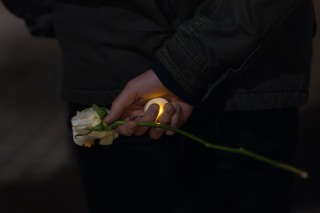 A student holds a fake candle and a rose behind their back during the vigil for Lucas.